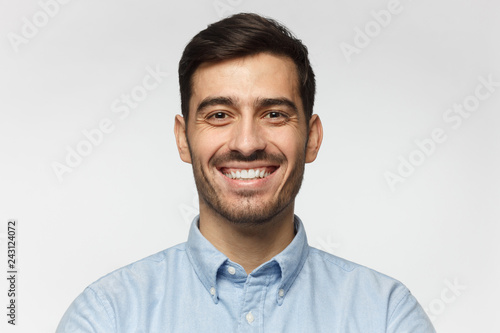 Close-up portrait of handsome business man laughing, isolated on gray background © Damir Khabirov