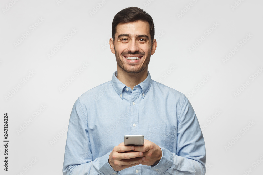 Portrait of positive business man laughing out loud while using mobile phone, isolated on gray background Portrait of positive business man laughing out loud while using mobile phone, isolated on gray background