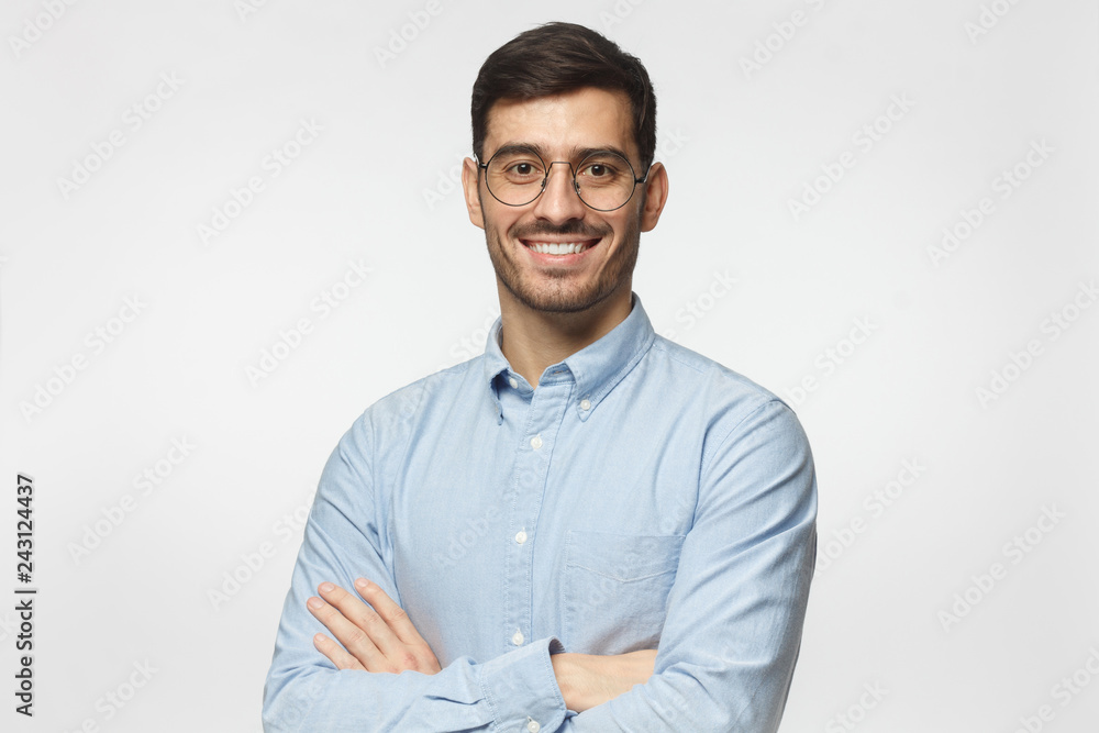 Modern businessman in blue shirt standing with crossed arms, isolated on gray background Modern businessman in blue shirt standing with crossed arms, isolated on gray background