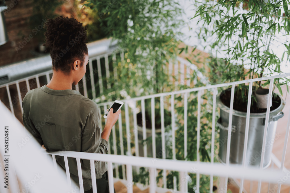 Fototapeta premium Afro american girl using cellphone while standing on stairs