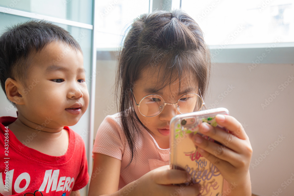 Sister and brother child playing smartphone in room Sister and brother child playing smartphone in room
