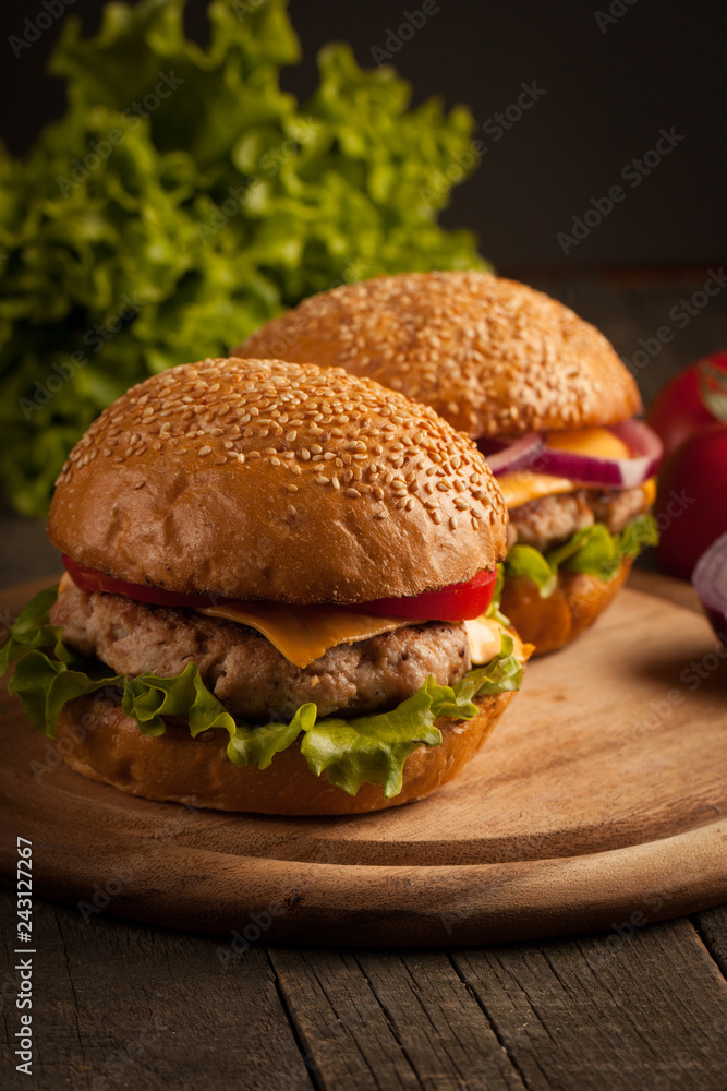 Home made hamburger with beef, onion, tomato, lettuce and cheese. Fresh burger close up on wooden rustic table with potato fries, beer and chips. Cheeseburger. Home made hamburger with beef, onion, tomato, lettuce and cheese. Fresh burger close up on wooden rustic table with potato fries, beer and chips. Cheeseburger.