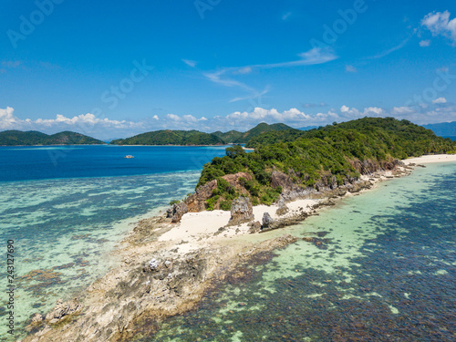 Aerial view of tropical beach on the island Malcapuya. Beautiful tropical island with sand beach, palm trees. Tropical landscape with shore and boat. Palawan, Philippines
