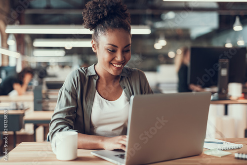 Beautiful afro american lady working on laptop in modern office