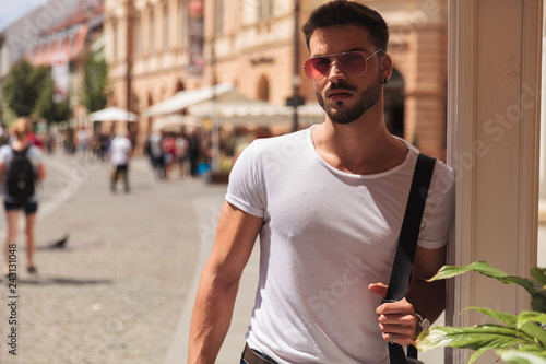 portrait of attractive casual man with red sunglasses standing