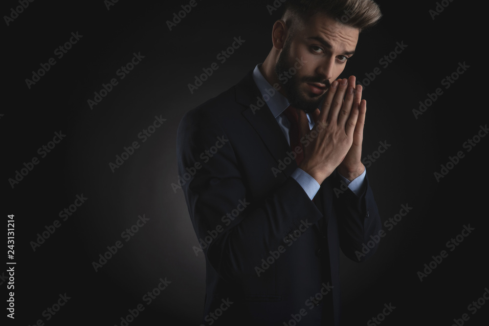 portrait of young businessman in navy suit praying