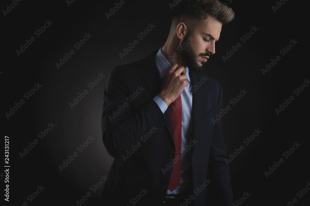 portrait of businessman looking down to side and fixing tie portrait of businessman looking down to side and fixing tie