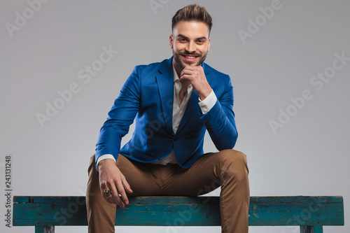 pensive and happy smart casual man in blue suit sitting