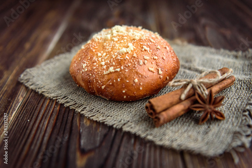 Cinnamon bun with cinnamon on wooden background.