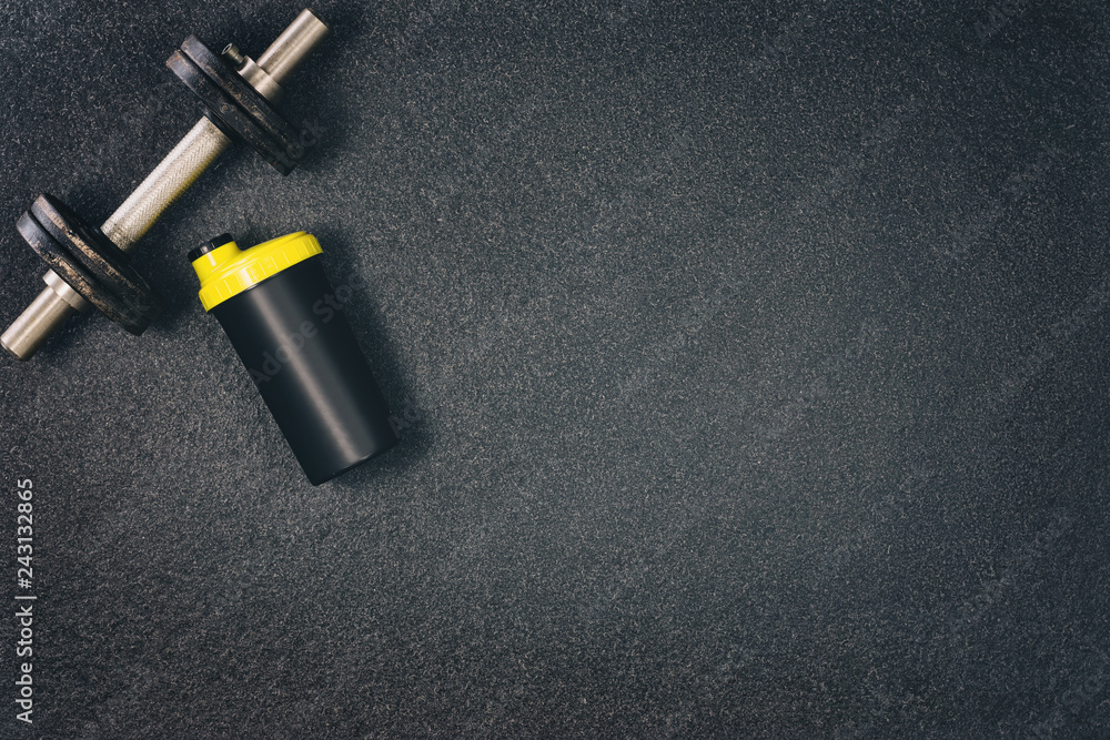 Naklejka premium Fitness or bodybuilding concept background. Product photograph of old iron dumbbells on black grey, conrete floor in the gym. Photograph taken from above, top view with lots of copy space