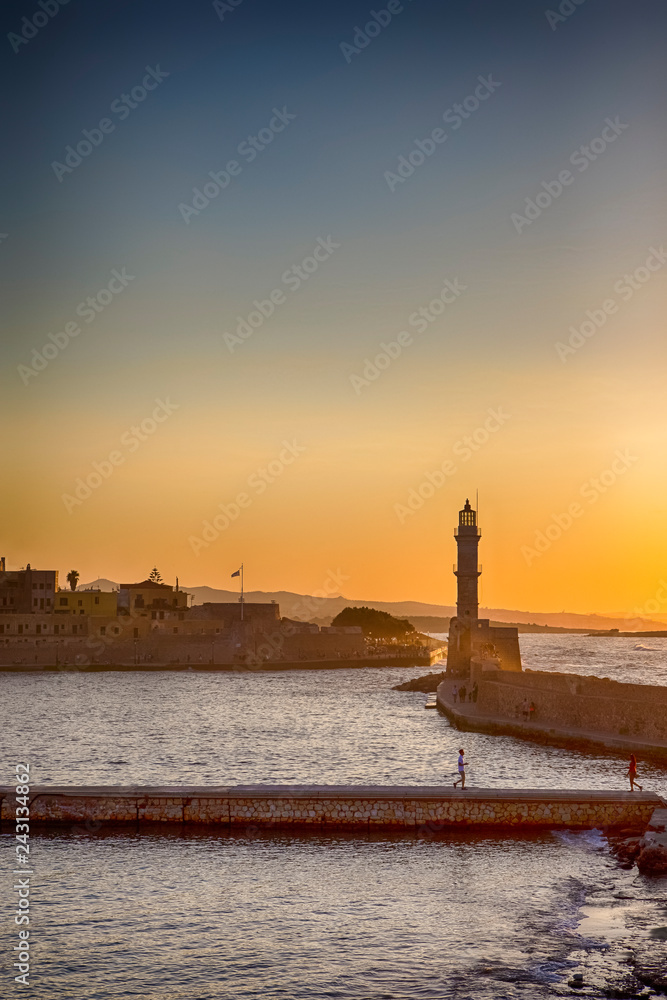 European Travel Destinations. City of Chania and Ancient Venetian Port With Lighthouse in Foreground Taken At Golden Hour in Crete, Greece.