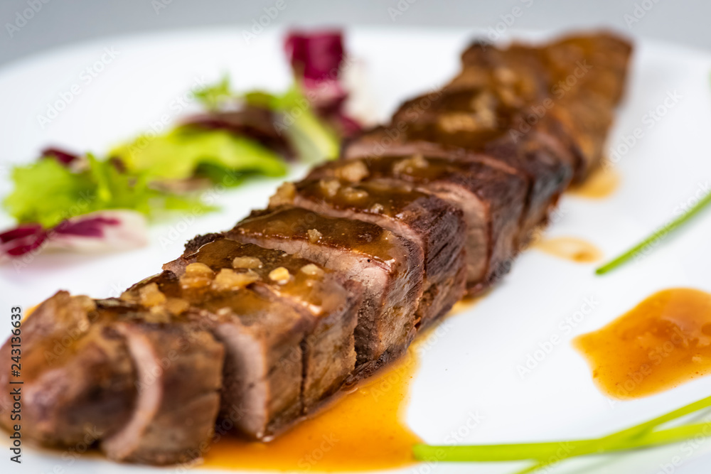 a sliced steak poured with onion decorated with lettuce leaves a sliced steak poured with onion decorated with lettuce leaves
