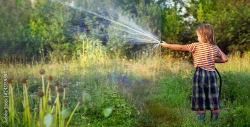 Boy hose garden on a summer day