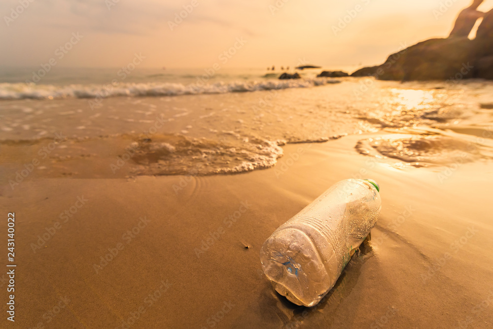 Obraz premium Empty plastic bottle on the beach with sea waves at morning sunrise.Thailand.