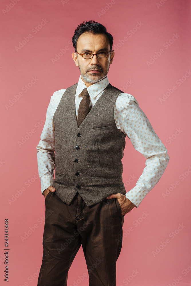 Φωτογραφία Knee length portrait of a mature man in vest and glasses, isolated on pink