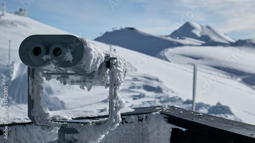 Snow covered outdoor stationary viewing binoculars or also known as a landscape viewing telescope.