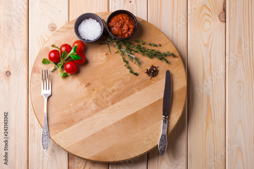 food board with salt, tomatoes, pepper, spices and rosmarine on wooden background. Healthy vegetarian food. Recipe, menu, mock up, cooking. photo