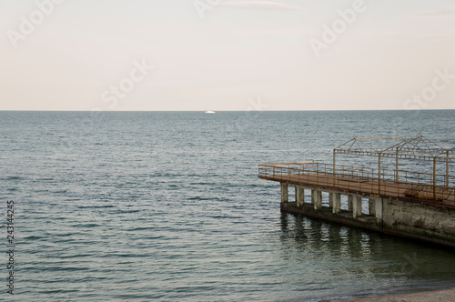 Black Sea. Water with no waves and little boat far away. Calm. Mainly cloudy weather. Blue and grey color. Before rain