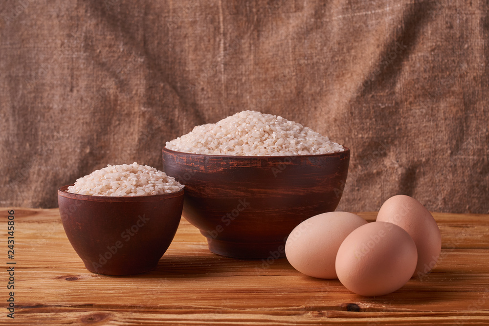 White rice in clay bowl on table and eggs on wood background. Concept asian food White rice in clay bowl on table and eggs on wood background. Concept asian food