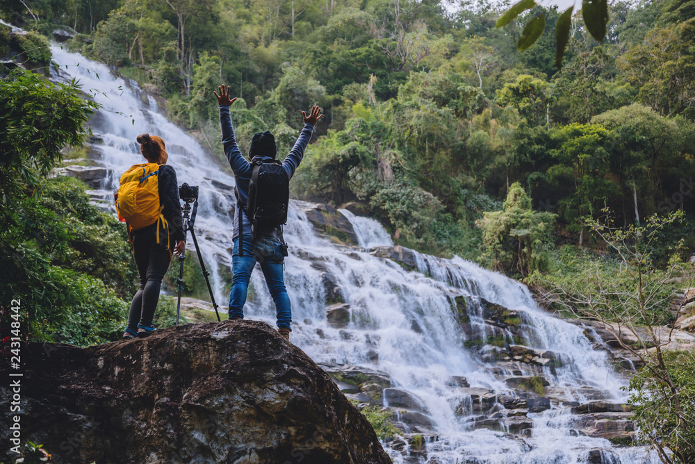 Obraz premium Asian couple travel nature. Travel relax. Stand landscapes Natural Touch Stand to see beautiful waterfalls mae ya at Chiangmai in Thailand.