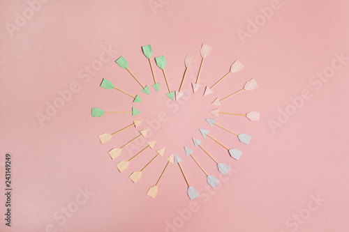 Paper Cupid arrow and heart symbols on pink background. Flat lay, top view Valentines Day background love concept.