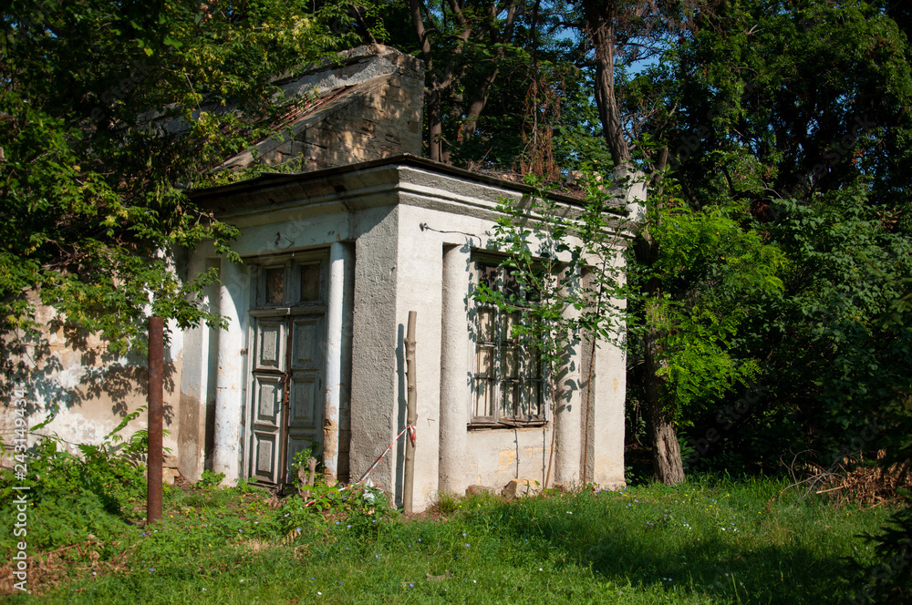 Old ancient white destroyed stone house on the green yard with trees around. Poverty and misery, South, summer Old ancient white destroyed stone house on the green yard with trees around. Poverty and misery, South, summer
