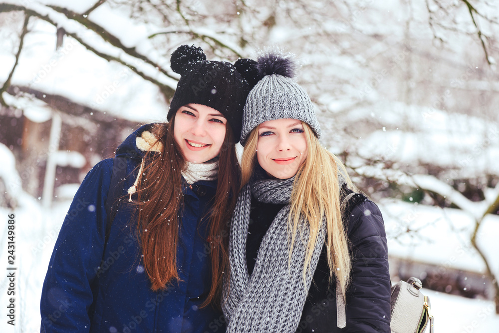 funny and happy two beautiful girlfriends walk in the winter, a lot of snow and winter clothes. blonde and brunette emotions