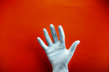 Hand in medical latex gloves. Hand palm up. Red background. Close-up.