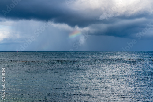 Rainclouds and a rainbow over the North Sea in Benthall, Northumberland, England, UK