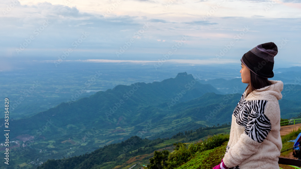 Naklejka premium Woman tourist in a sweater dress watching the beautiful nature landscape of the forest and mountain during the sunrise at Phu Thap Boek Viewpoint Phetchabun, Thailand, 16:9 widescreen