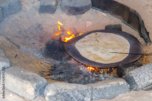 Canvas-taulu Traditional arabic pita bread cooking on fire in bedouin dwelling