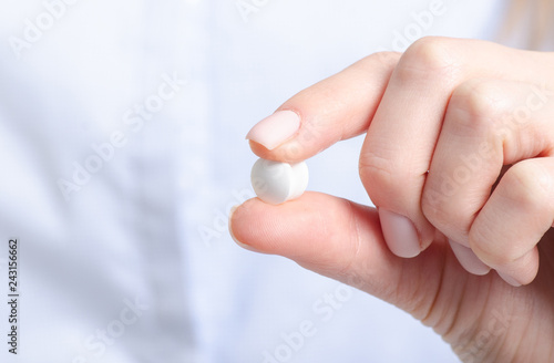 White pills medicine in woman hand on blur background  pharmacy concept