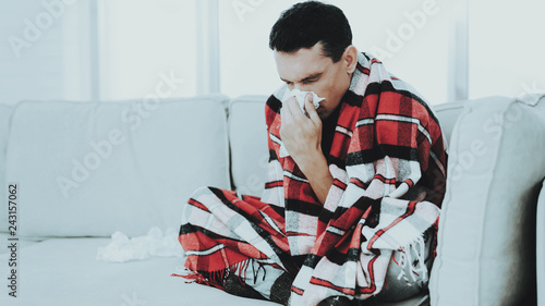 Man with Cold Sitting on Sofa in Checkered Blanket