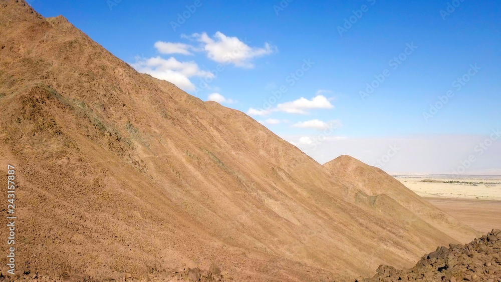 Desert landscape - Aerial image of mountains and dry land with blue cloudy sky in the background. Desert landscape - Aerial image of mountains and dry land with blue cloudy sky in the background.