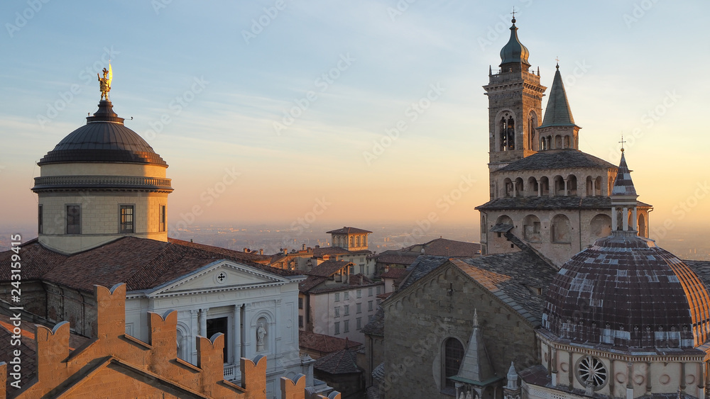 Bergamo, Italy. The old town. Aerial view of the Basilica of Santa Maria Maggiore and the dome of the cathedral during the sunset. In the background the Po plain