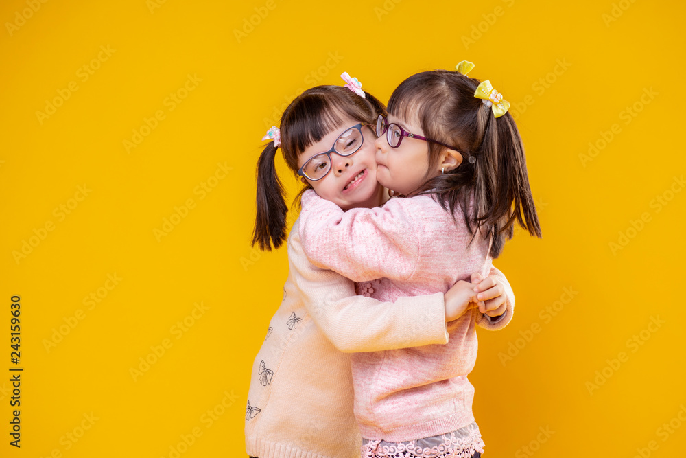 Charming positive sisters with chromosome abnormality hugging each other - obrazy, fototapety, plakaty 