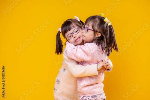Charming positive sisters with chromosome abnormality hugging each other photo