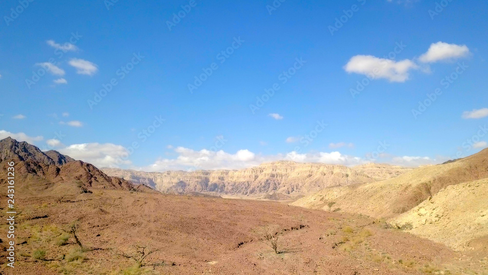 Desert landscape - Aerial image of mountains and dry land with blue cloudy sky in the background. Desert landscape - Aerial image of mountains and dry land with blue cloudy sky in the background.