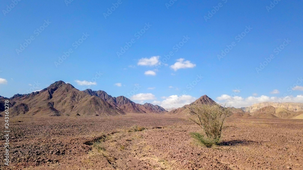 Desert landscape - Aerial image of mountains and dry land with blue cloudy sky in the background. Desert landscape - Aerial image of mountains and dry land with blue cloudy sky in the background.