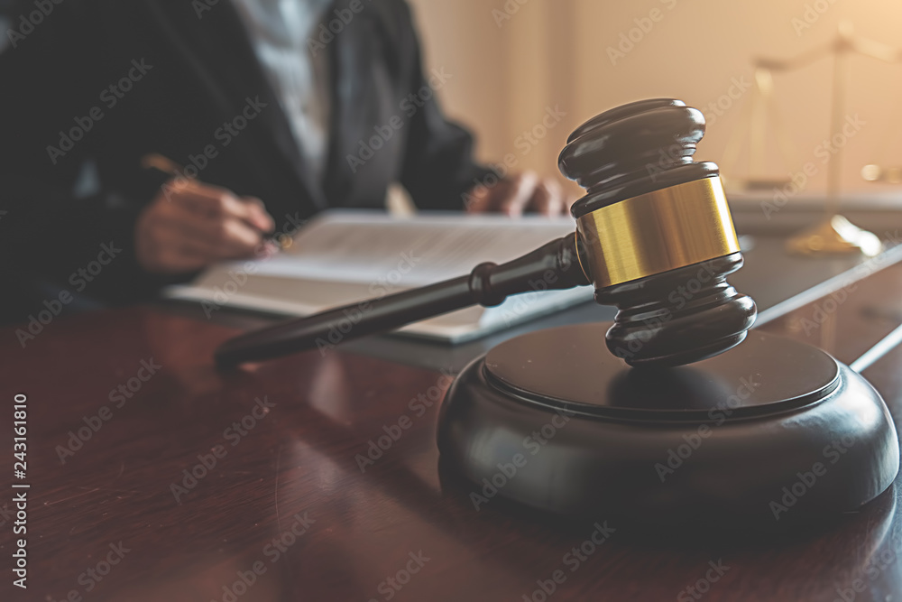 Justice and Law concept. Legal counsel presents to the client a signed contract with gavel and legal law or legal having team meeting at law firm in background Justice and Law concept. Legal counsel presents to the client a signed contract with gavel and legal law or legal having team meeting at law firm in background