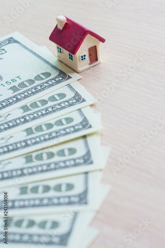 Selective focus miniature small house with dollar bank notes, real estate business investment, loan from a bank for housing.