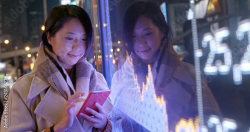 Woman check on cellphone over the stock market data screen board