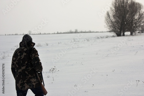 hunter walking on the snowy field in winter