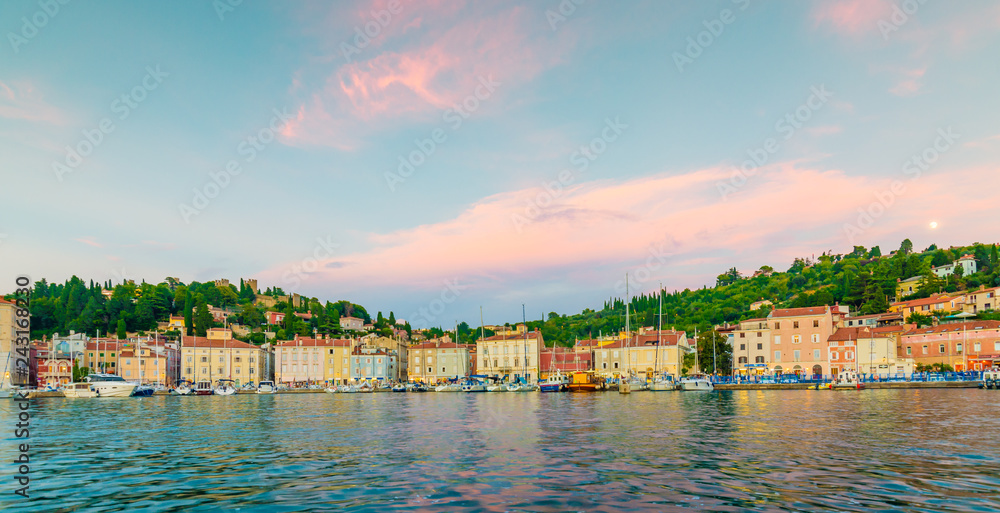 Piran harbor during the sunset. Soft and warm light above boats and Piran houses.