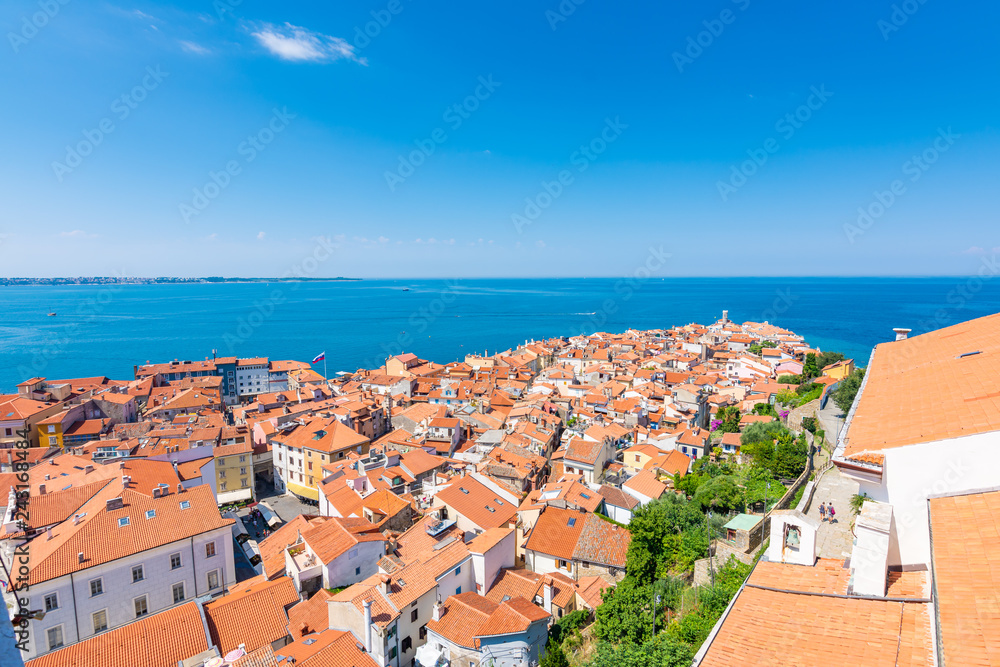 Aerial panoramatic view of Piran city, Slovenia. Look from tower in church. In foreground are small houses, Adriatic sea in background. Summer weather in famous tourist destination