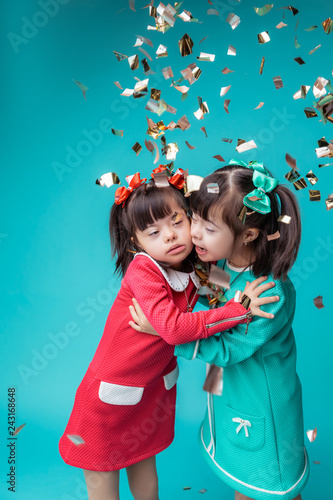Pretty young sisters in colorful dresses hugging each other