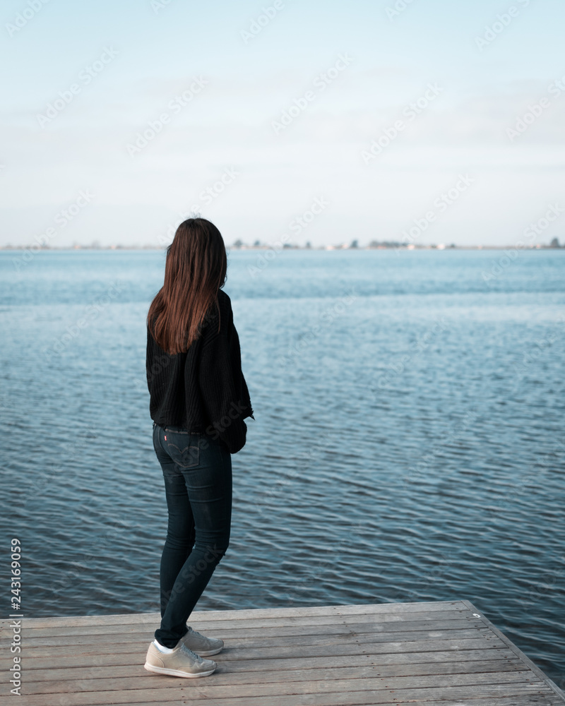 Imagen de una joven mujer mirando hacia el mar en un muelle de Tarragona Imagen de una joven mujer mirando hacia el mar en un muelle de Tarragona