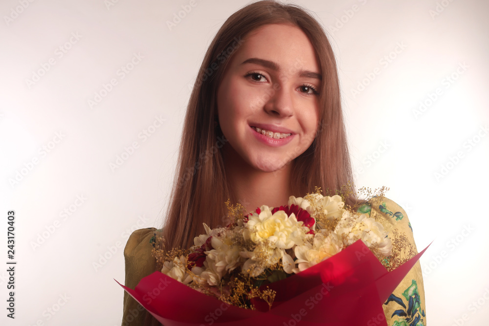 The portrait of an young blonde brunette lady with flowers isolated over white wall background wearing colorful bright dress The portrait of an young blonde brunette lady with flowers isolated over white wall background wearing colorful bright dress