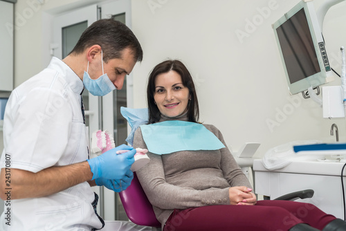Woman in dentistry looking at model of prosthesis
