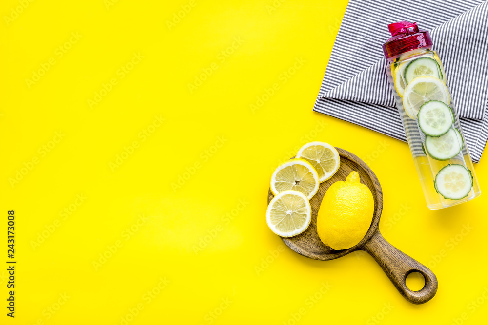 Make detox fruit water. Slices of lemon and cucumber in bottle on yellow background top view space for text Make detox fruit water. Slices of lemon and cucumber in bottle on yellow background top view space for text